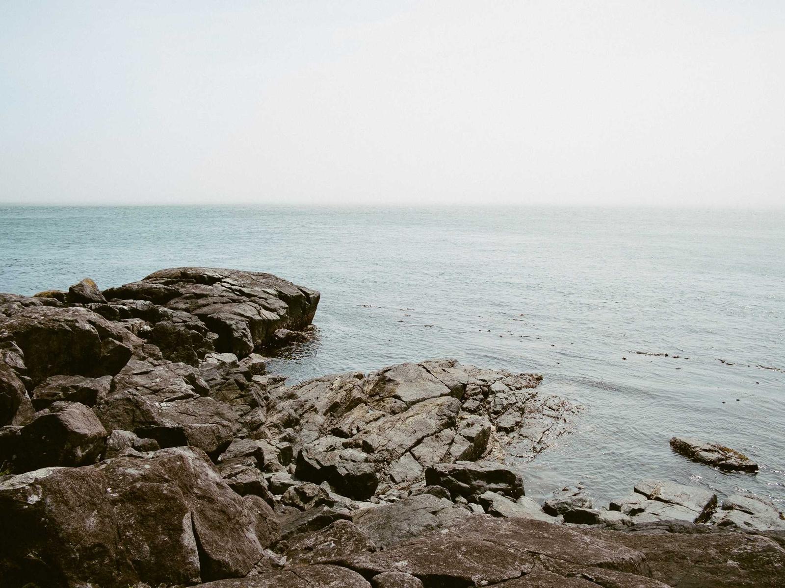 A quiet ocean coastline beneath a pale sky
